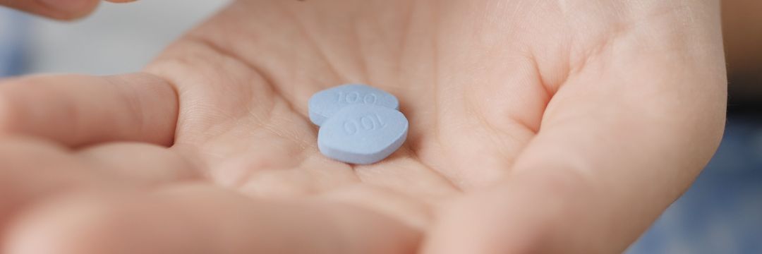 Man holding two blue pills 