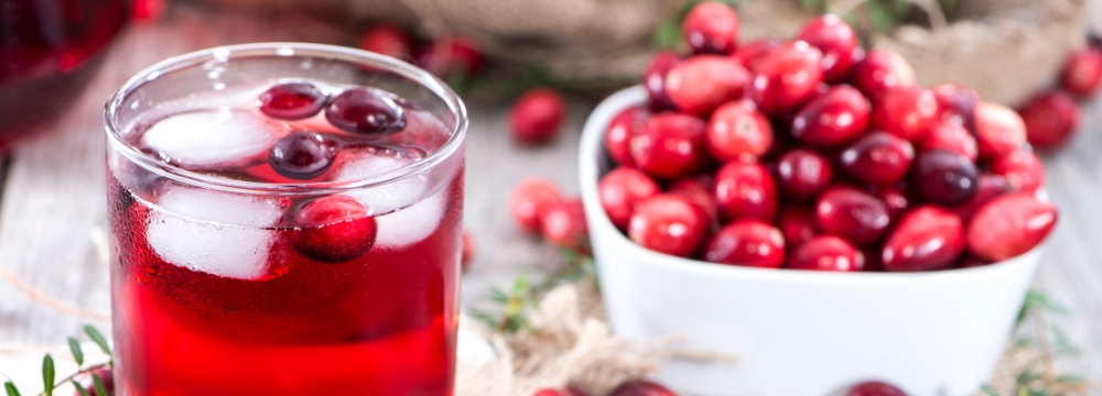Glass of cranberry juice next to bowl of cranberries