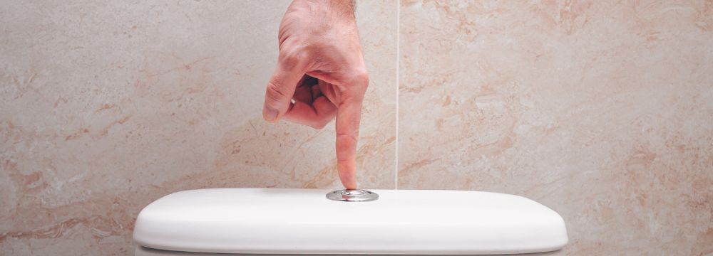 Man pushing flush button on top of toilet